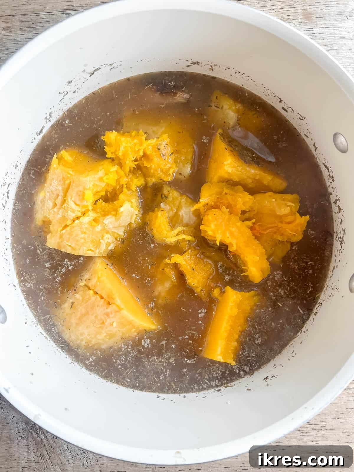 Roasted butternut squash added to a soup pan.