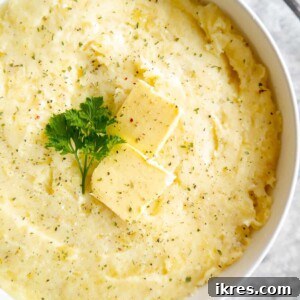 Mashed potatoes cottage cheese in a large bowl with butter on top.