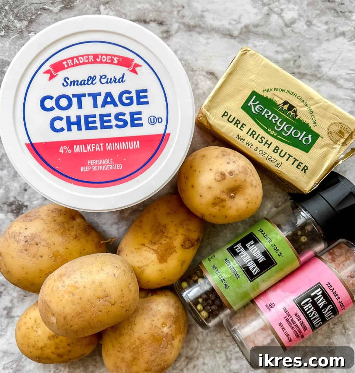 Whipped Cottage Cheese Potatoes 3 Fresh ingredients laid out on a kitchen counter, including gold potatoes, a tub of cottage cheese, a stick of butter, and small bowls of salt and pepper – all essential for making cottage cheese mashed potatoes.