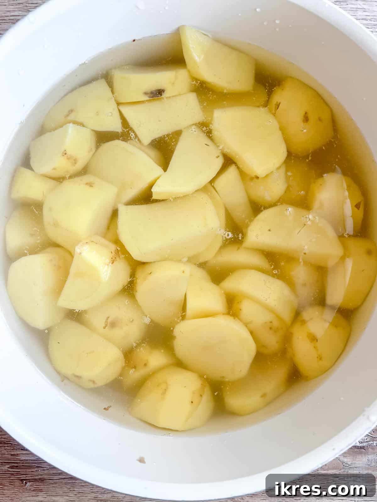 Whipped Cottage Cheese Potatoes 5 Cubed potatoes submerged in a large pot of boiling water on a stove, cooking until tender for mashing.