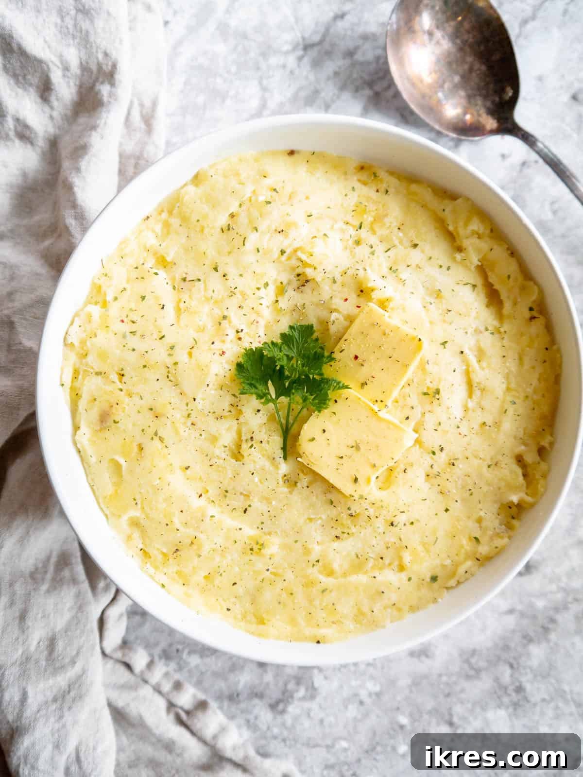 Whipped Cottage Cheese Potatoes 7 A bowl of smooth, creamy mashed potatoes, enriched with cottage cheese, garnished with fresh parsley and a sprinkle of black pepper, ready for serving.