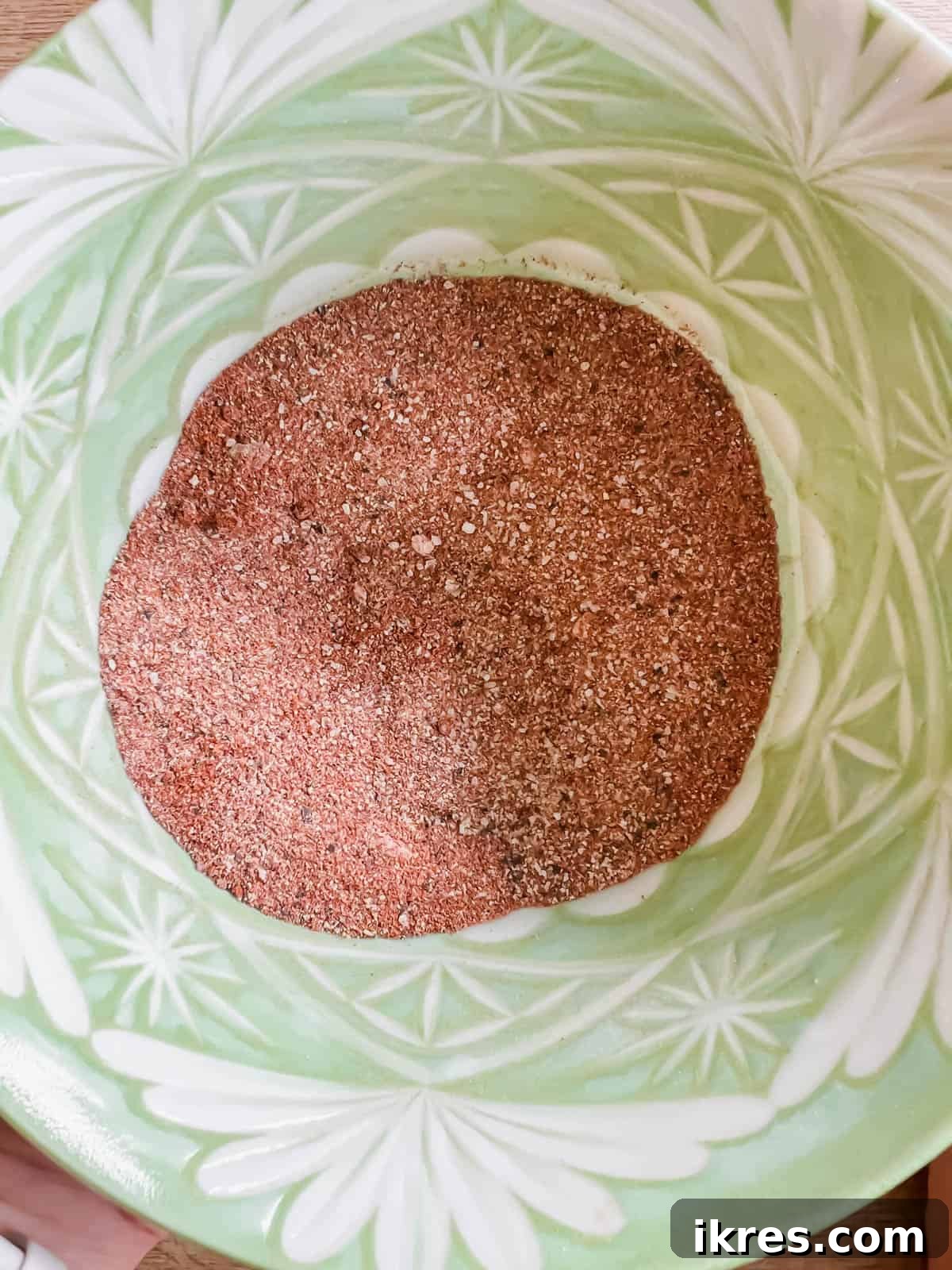 Bowl containing a vibrant paprika and spice mixture for seasoning beef.