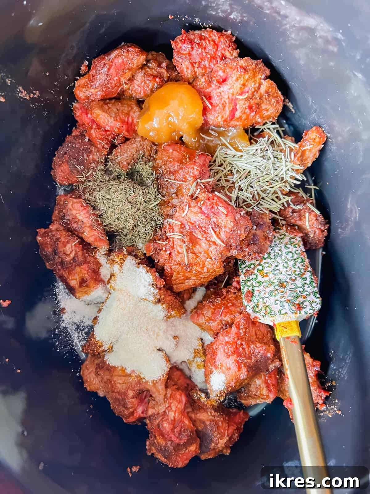 Seared stew meat and seasoning mixture transferred into a slow cooker.