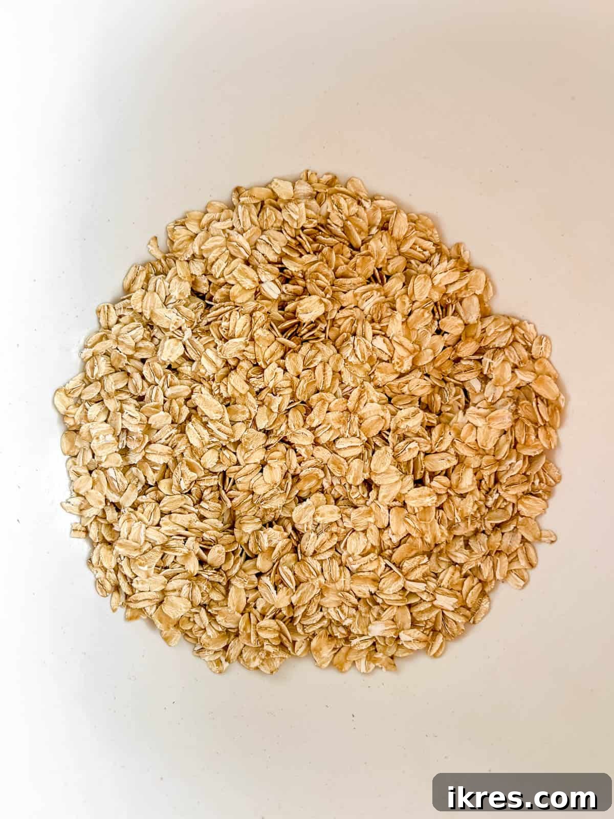 Dry ingredients for monster cookies, including rolled oats, baking soda, and salt, perfectly measured in a mixing bowl.
