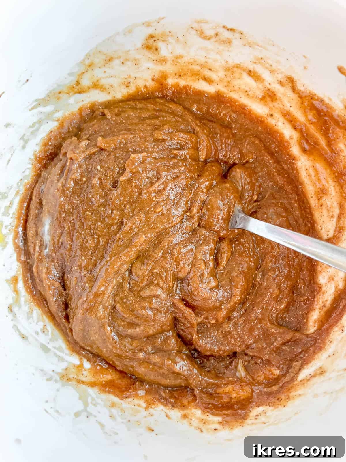 Wet ingredients for flourless monster cookies, including brown sugar, olive oil, eggs, vanilla extract, and almond butter, expertly blended in a separate bowl.