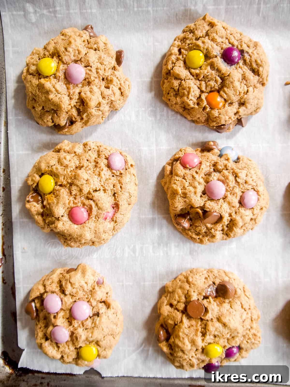 Freshly baked no-flour monster cookies, golden brown with melty chocolate, cooling on a rack, showcasing their perfect spread.