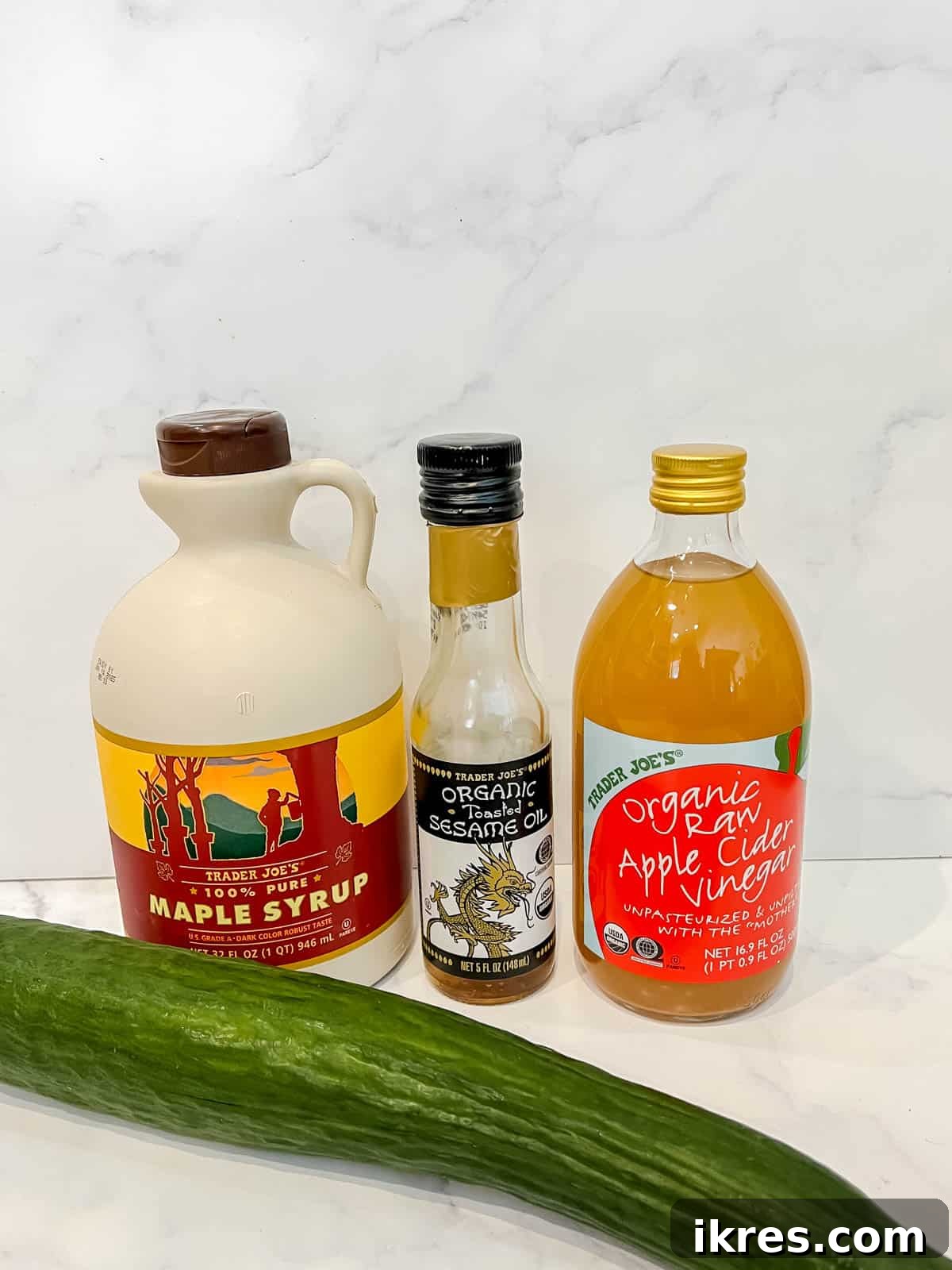 Crisp Asian Quick Pickles 3 A flat lay of all necessary ingredients including English cucumber, maple syrup, apple cider vinegar, and sesame oil, for quick Asian pickled cucumbers.
