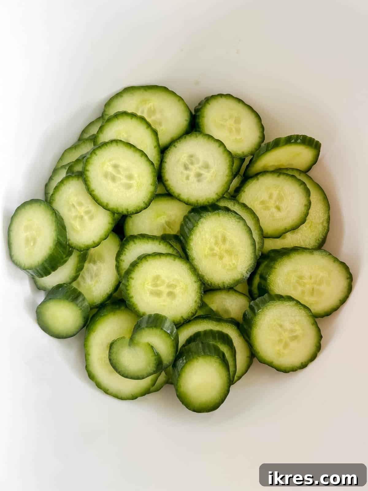 Crisp Asian Quick Pickles 4 Thinly sliced English cucumbers neatly arranged in a large mixing bowl.