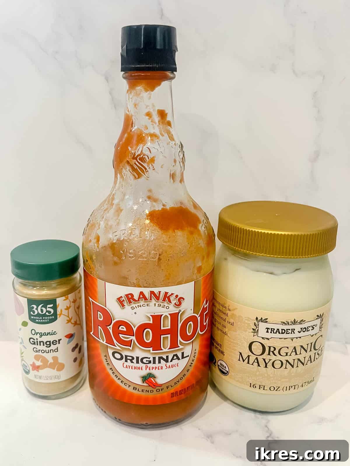 Close-up of ingredients for making spicy mayo, showing mayonnaise, hot sauce, and ground ginger.
