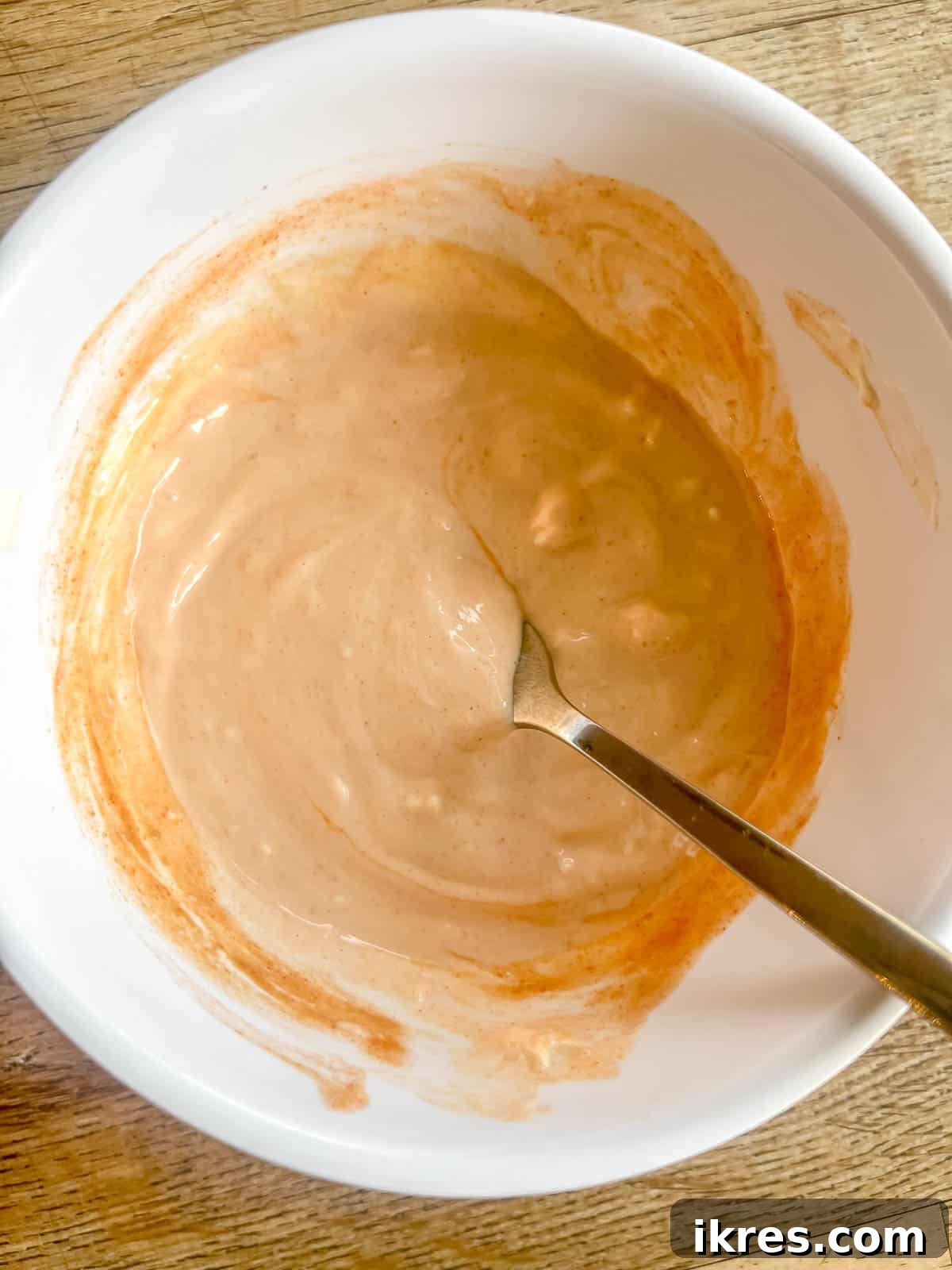 Creamy spicy mayo in a small serving bowl, garnished with a sprinkle of red pepper flakes.