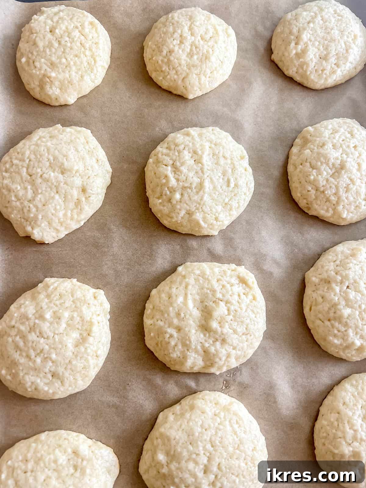 Pillowy Cottage Cookies 12 Baked cottage cheese sugar cookies on a baking sheet, showing golden bottoms and pale tops.