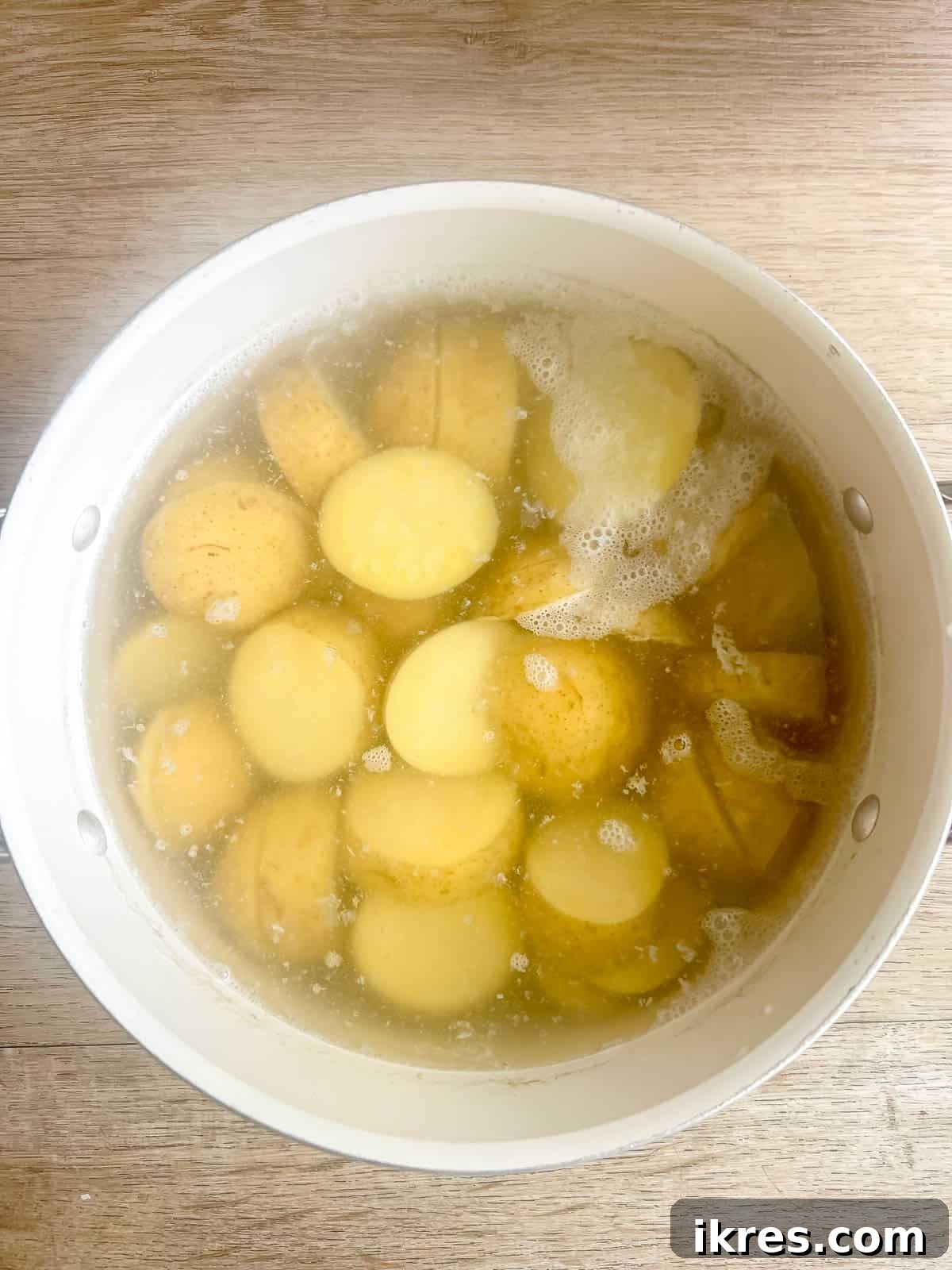 Sliced gold potatoes boiling in a large pot on the stove.
