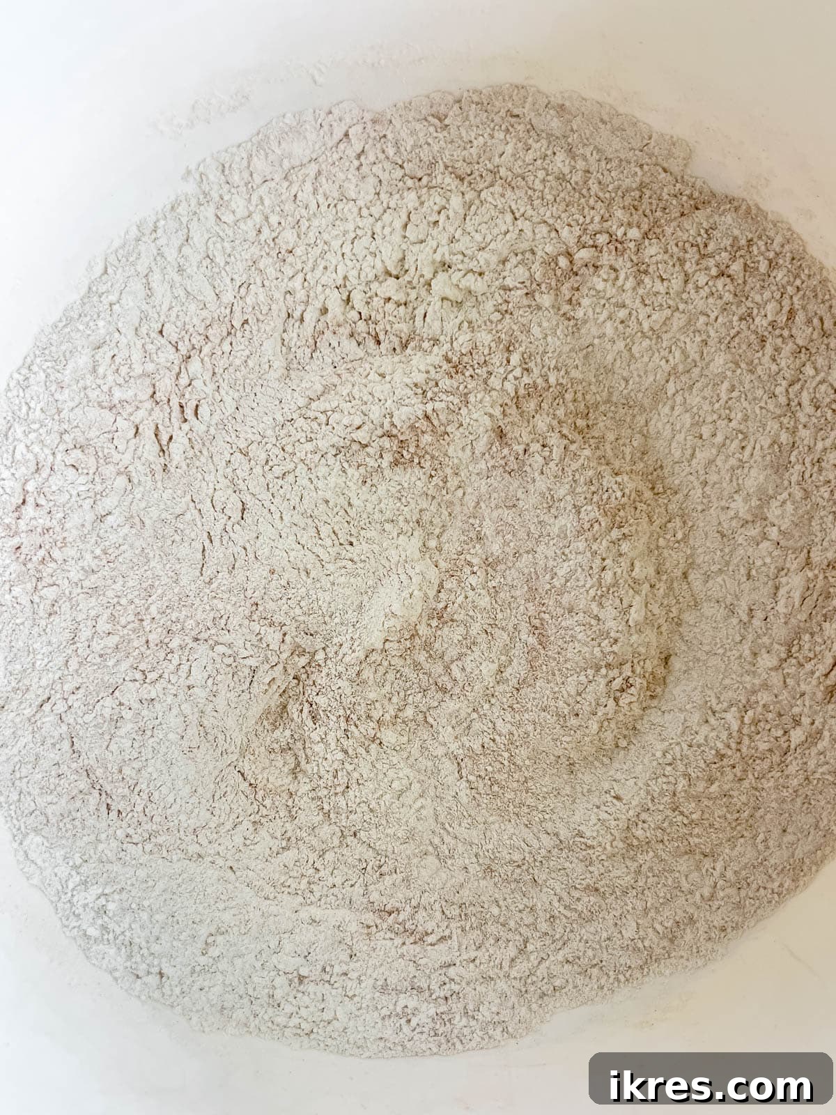 Dry ingredients for banana bread recipe with Greek yogurt, including flour, cinnamon, baking soda, and salt, in a separate bowl.