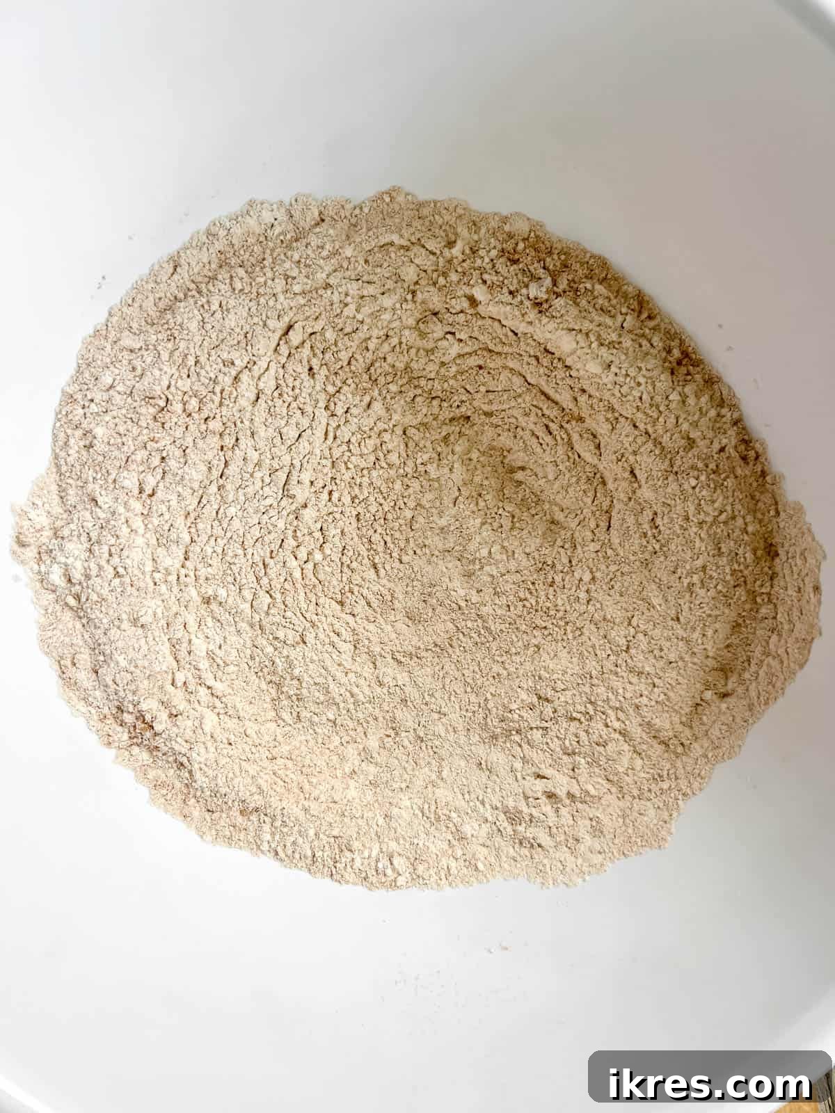 Dry ingredients for pumpkin pancakes (baking powder, flour, cinnamon, ginger, nutmeg) being mixed in a separate bowl.