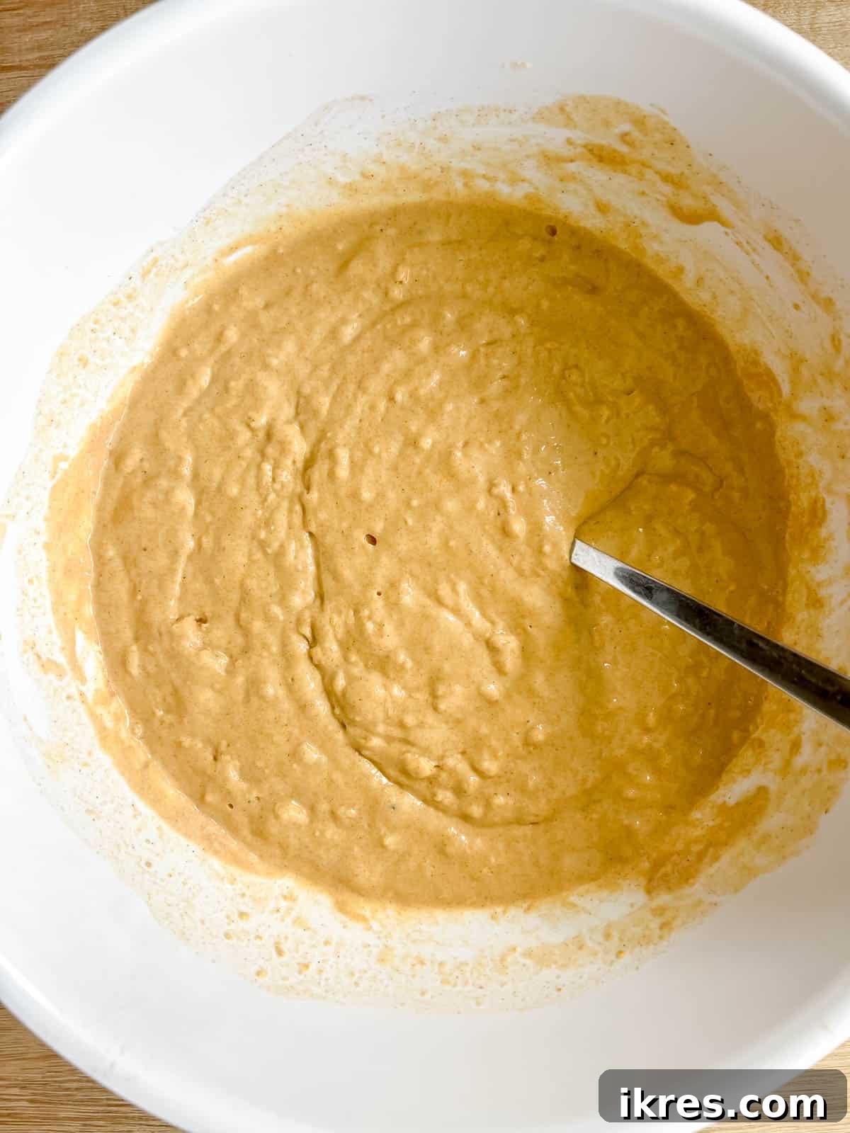 Milk being gradually added to the thick pumpkin pancake batter, to reach the right consistency.