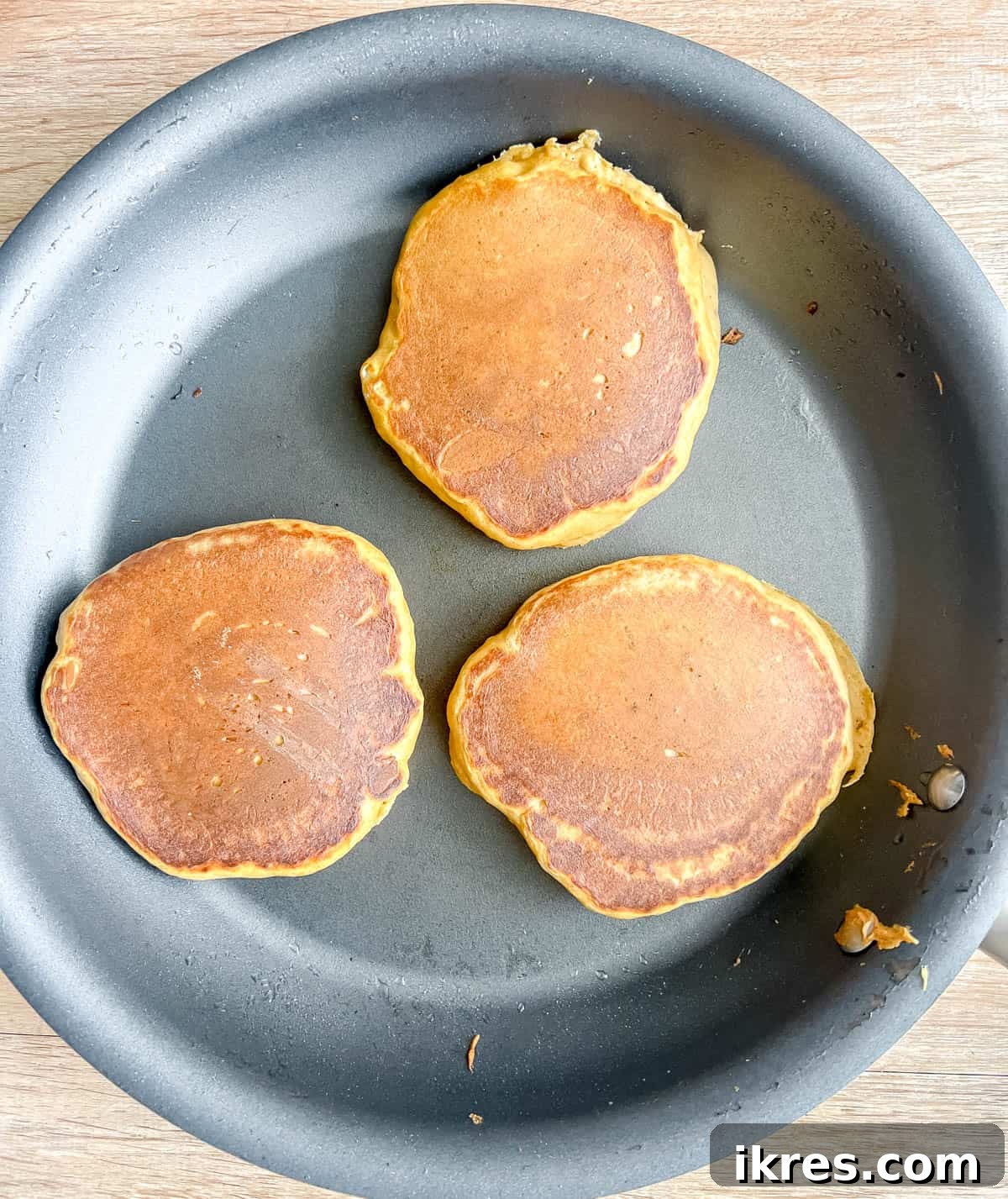 Healthy pumpkin pancakes being flipped on a pan, revealing a golden-brown underside.