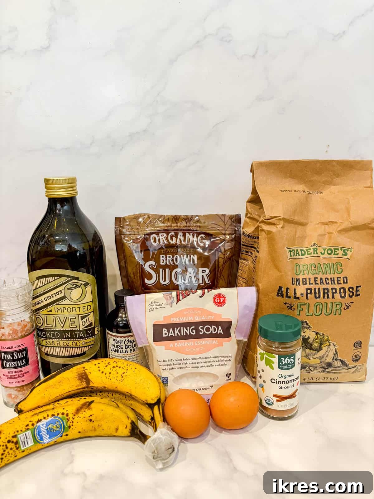 Golden Olive Oil Banana Bread 3 Individual ingredients laid out for making olive oil banana bread, including olive oil, eggs, bananas, and dry ingredients.