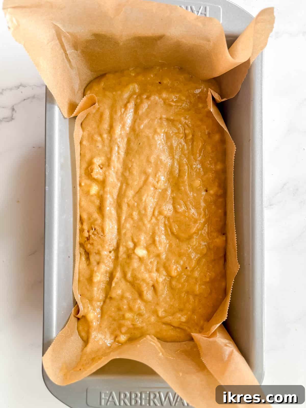 Golden Olive Oil Banana Bread 7 Olive oil banana bread batter carefully poured into a greased and parchment-lined loaf tin, ready for baking.