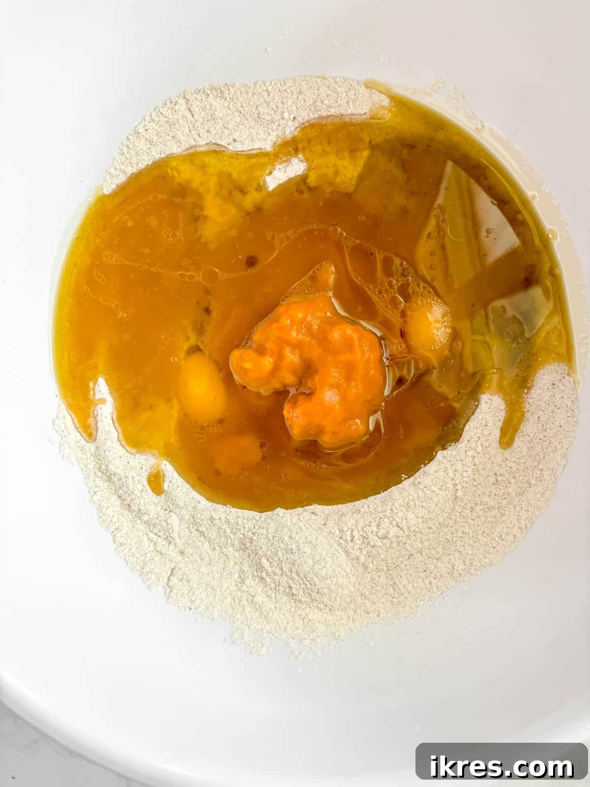 Autumn Spiced Dairy-Free Pumpkin Bread 6 Wet ingredients including eggs, pumpkin puree, olive oil, and water carefully poured into the well of the dry ingredients.