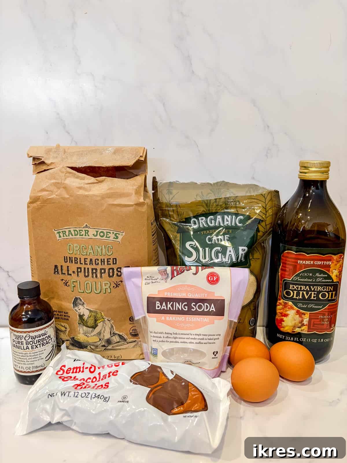 Liquid Gold Brownies 3 All ingredients laid out for making olive oil brownies: olive oil, chocolate chips, sugar, vanilla, eggs, flour, baking soda, and salt.