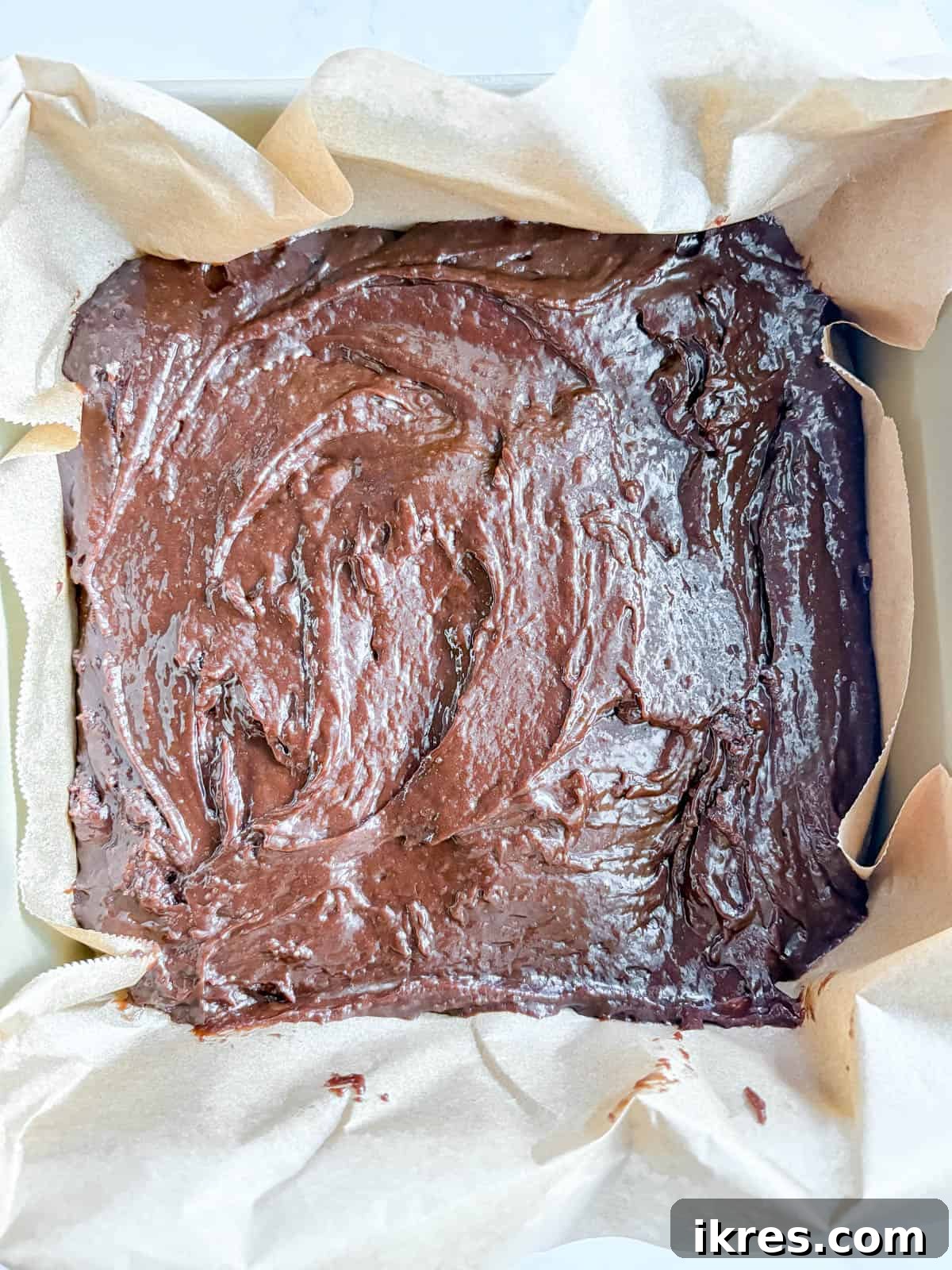 Liquid Gold Brownies 9 Olive oil brownie batter poured into a parchment-lined baking pan, ready for the oven.