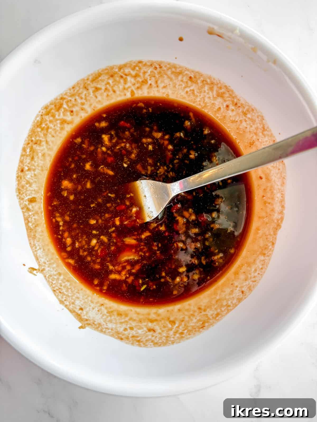 A small bowl filled with a glossy, light brown honey garlic sauce, ready to be poured.