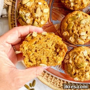 Pumpkin oat muffin sliced in half held in hands.