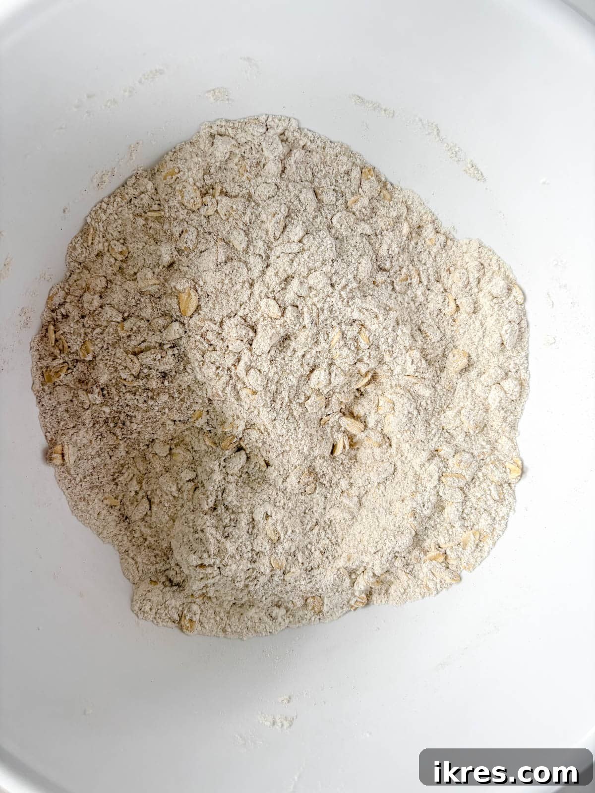 Plant-Based Pumpkin Spice Oat Muffins 4 Dry ingredients for pumpkin oat muffins, including flour, oats, sugar, and spices, mixed in a large bowl.