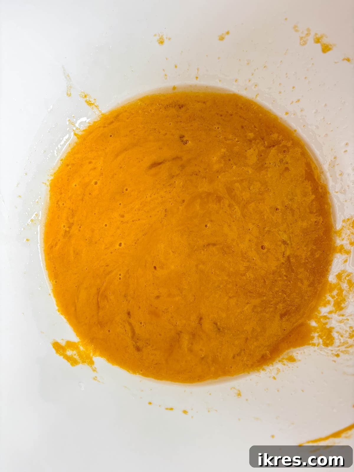 Plant-Based Pumpkin Spice Oat Muffins 5 Wet ingredients for healthy pumpkin oat muffins, including eggs, pumpkin puree, olive oil, and water, mixed in a separate bowl.
