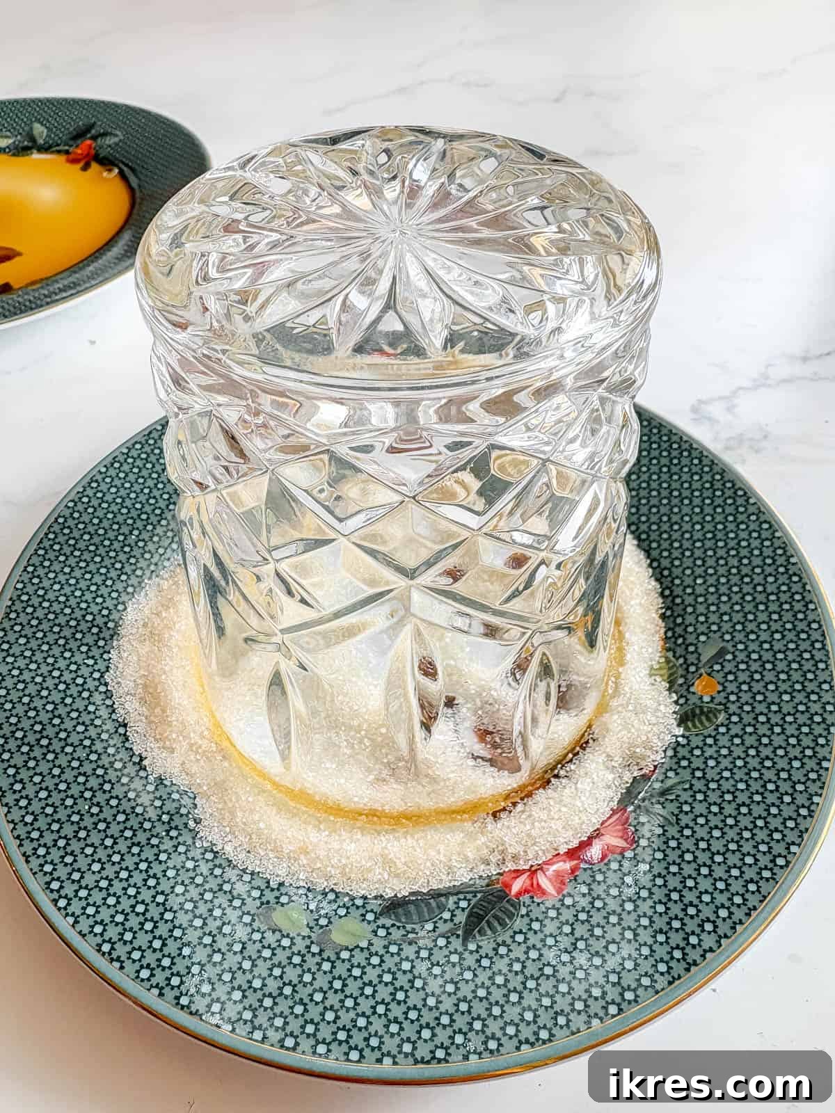 Glass rim, previously dipped in maple syrup, now being dipped in sugar on a small plate.