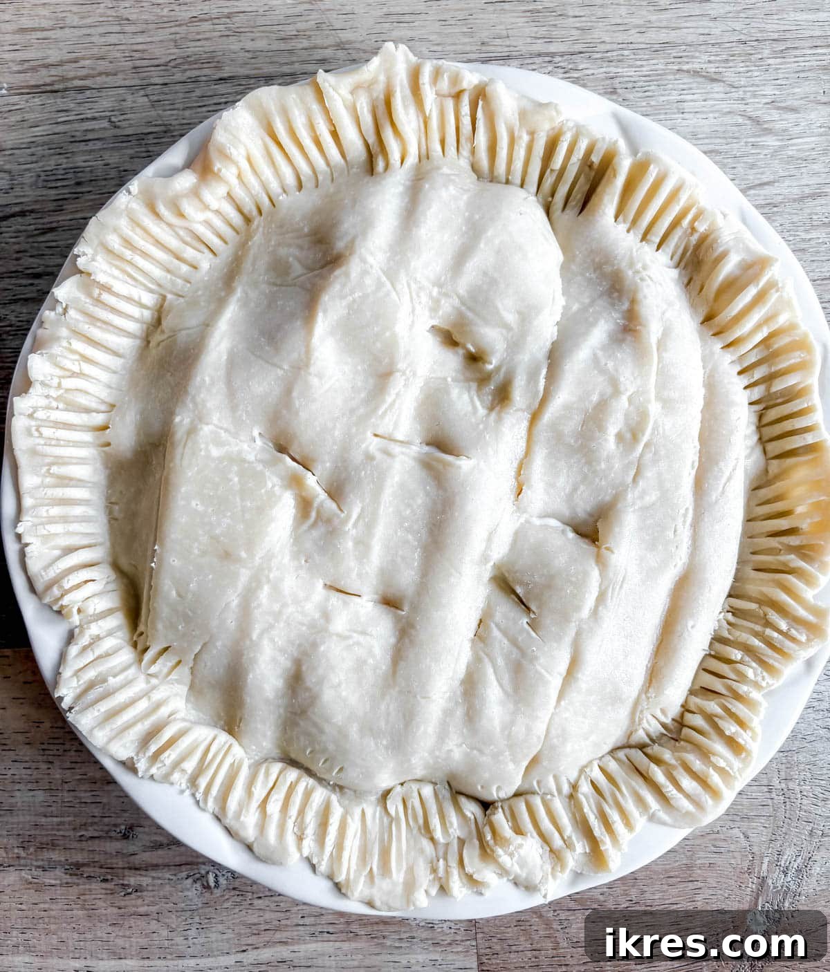 The second pie crust placed on top of the filling, with edges crimped to seal.