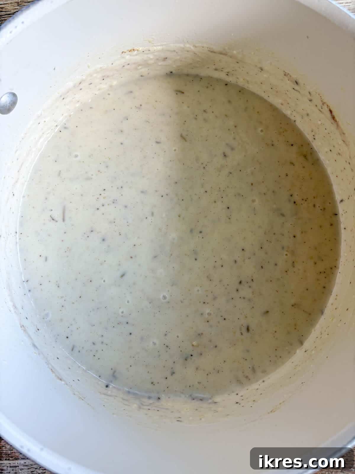A selection of spices being added to the creamy pot pie sauce.