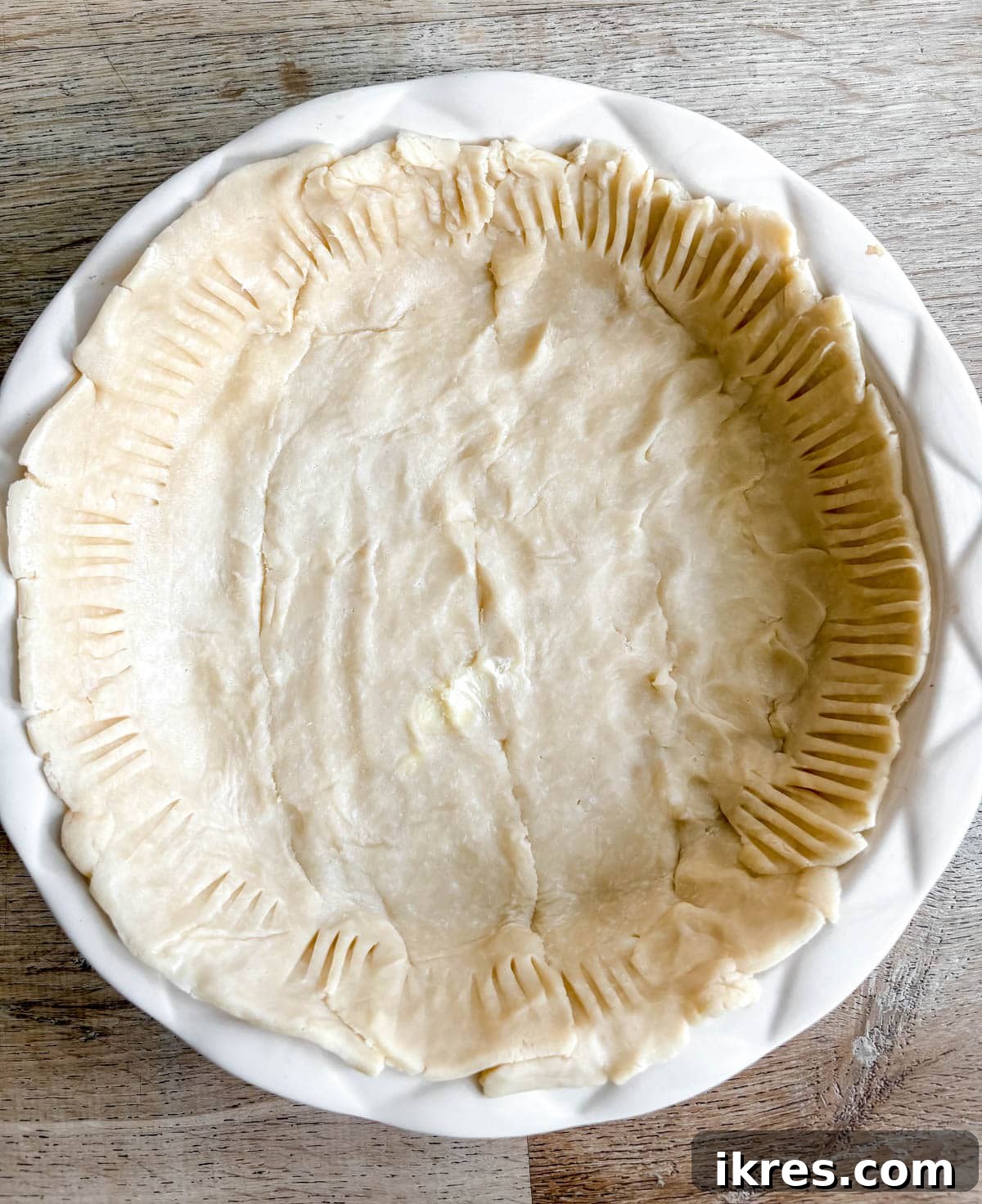One store-bought pie crust placed into a deep dish pie pan, with edges pressed down with a fork.
