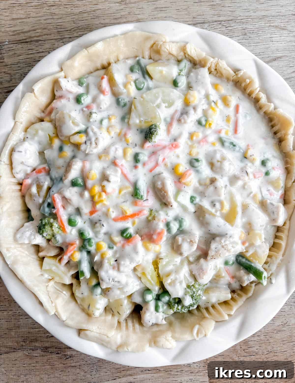 The chicken and vegetable pot pie filling poured into the pie crust-lined pan.