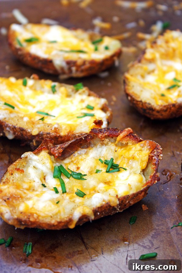 Ultimate Crispy Cheesy Bacon Potato Skins 6 A baking sheet filled with golden, crispy potato skins, generously topped with shredded cheese and bacon, fresh out of the oven and perfectly melted.