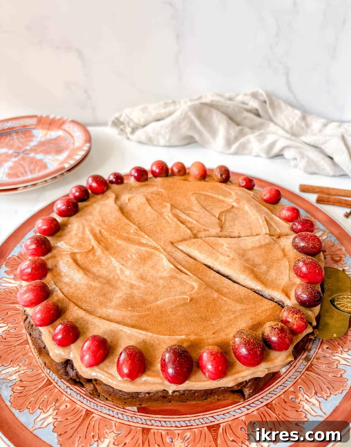 Spiced Gingerbread Cake with Tangy Cinnamon Cream Cheese Frosting 13 A sharp knife cutting a perfect slice of Christmas gingerbread cake with frosting and cranberries.