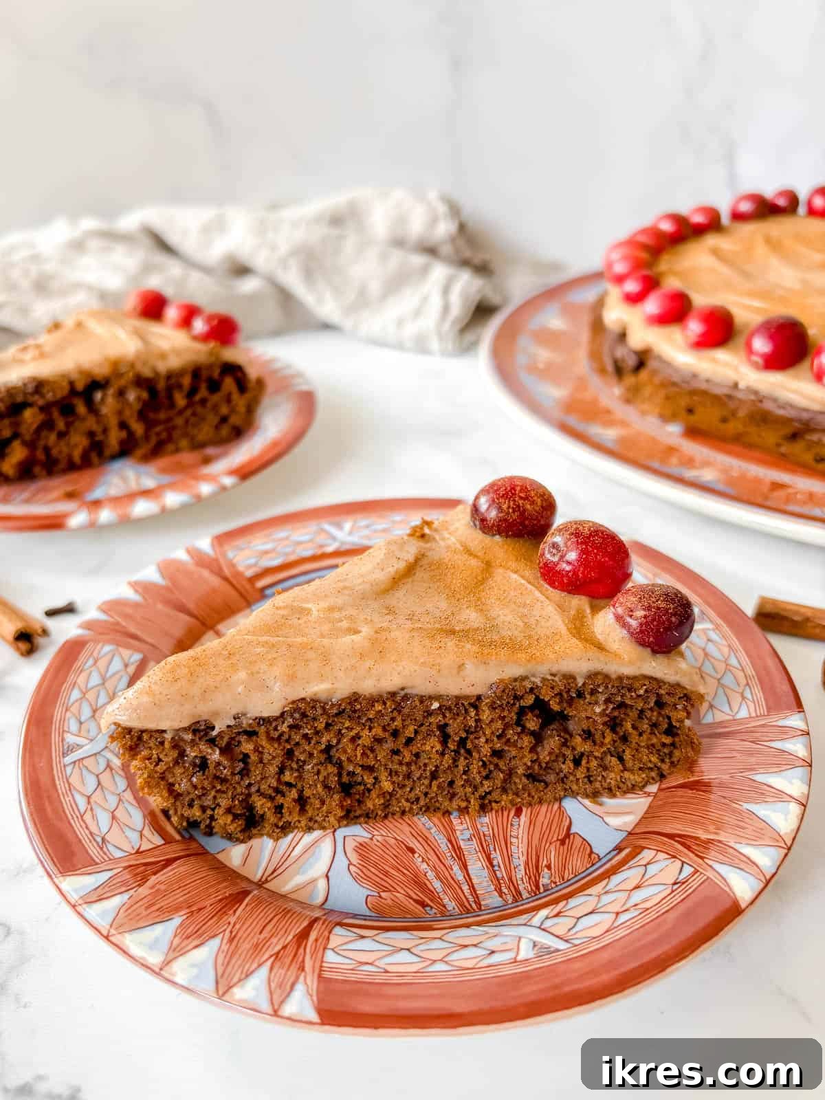 Spiced Gingerbread Cake with Tangy Cinnamon Cream Cheese Frosting 14 A perfectly portioned slice of gingerbread snacking cake with frosting and cranberries on a white plate, ready to be enjoyed.