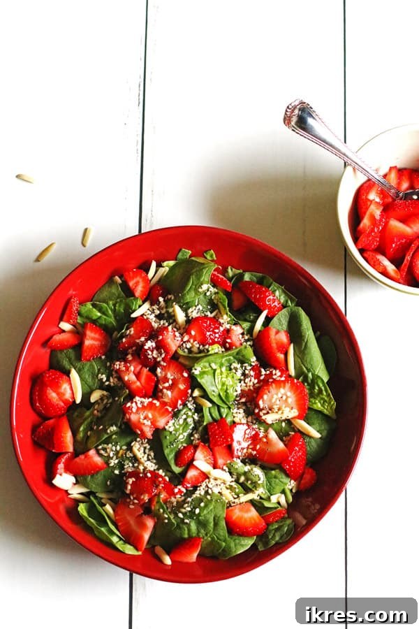 Vibrant Strawberry Spinach Salad with homemade dressing in a rustic red bowl, ready to be enjoyed.
