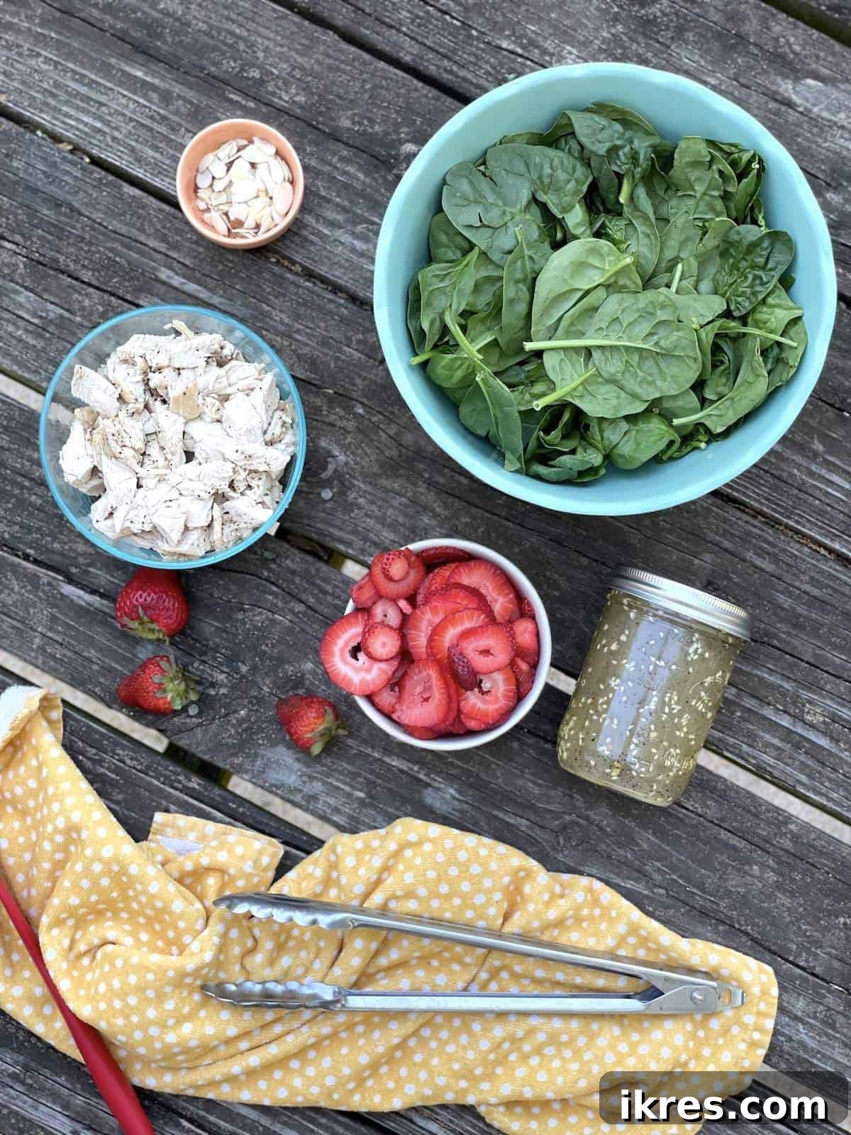 Array of fresh ingredients including spinach, strawberries, almonds, and chicken, ready for a hearty strawberry spinach chicken salad.