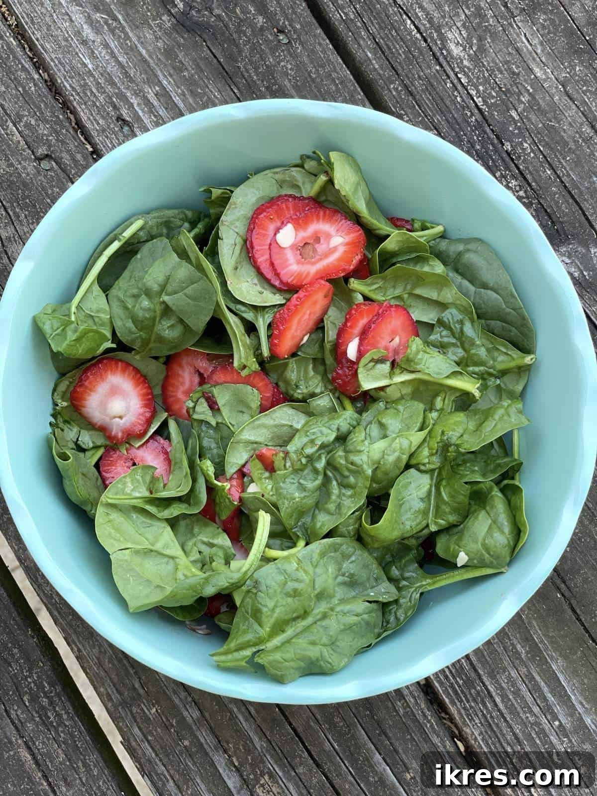 The strawberry and spinach salad, with almonds, gently tossed and ready for dressing application.