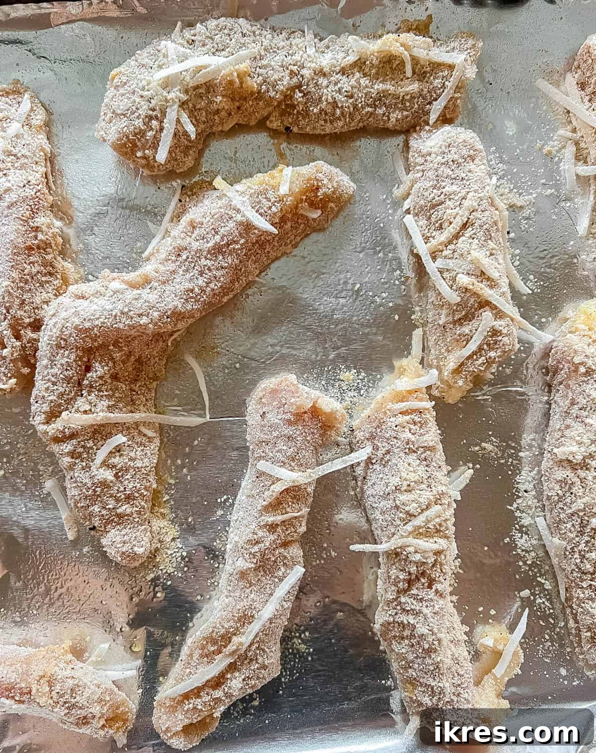 Prepared paleo chicken tenders laid out neatly on a baking sheet, ready to be placed in the oven.