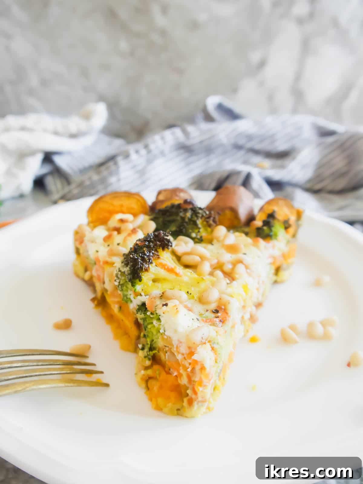 Vibrant Broccoli Carrot and Goat Cheese Quiche on a Gluten-Free Sweet Potato Crust 3 A perfectly cooked slice of carrot quiche with a sweet potato crust on a white plate, ready to be served.