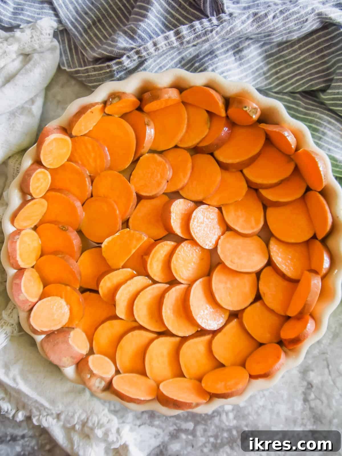 Vibrant Broccoli Carrot and Goat Cheese Quiche on a Gluten-Free Sweet Potato Crust 5 Thinly sliced sweet potatoes arranged in a circular pattern in a baking dish, forming the raw crust before baking.