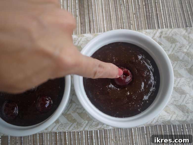 Cherries being added to the chocolate batter in ramekins.