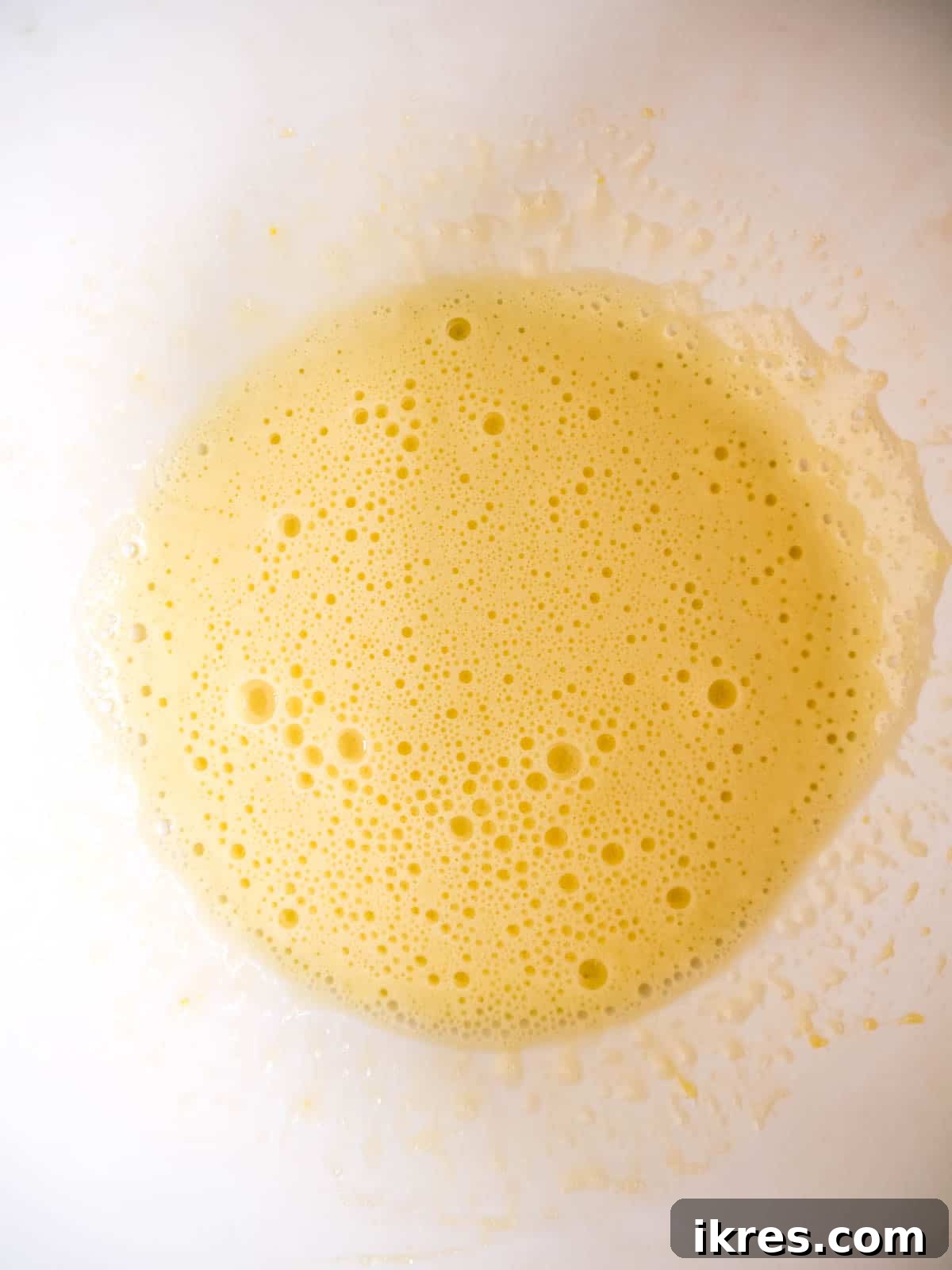 Eggs and sugar being whisked until light and foamy.