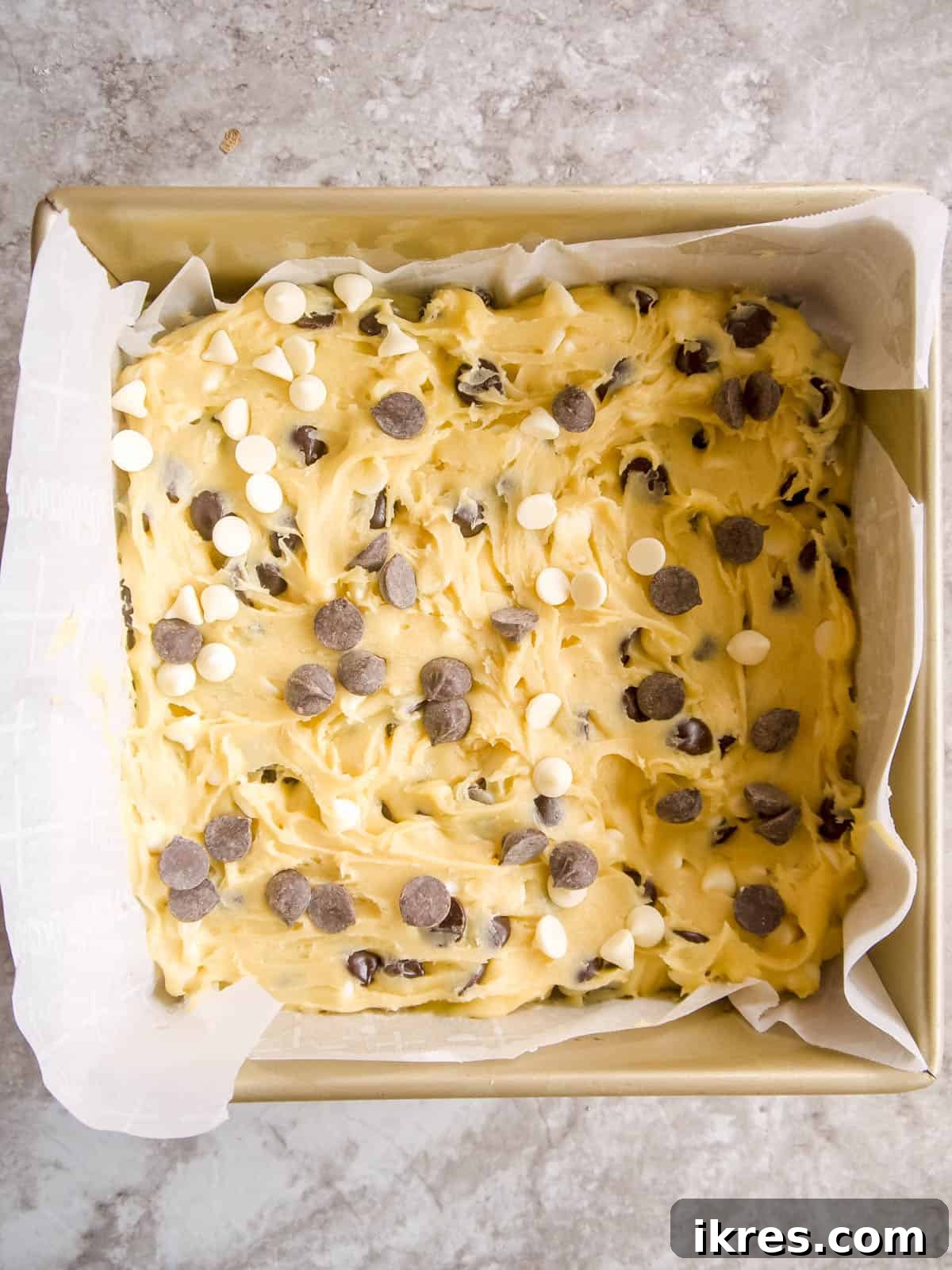 White chocolate brownie batter evenly spread in a baking pan, ready for the oven.