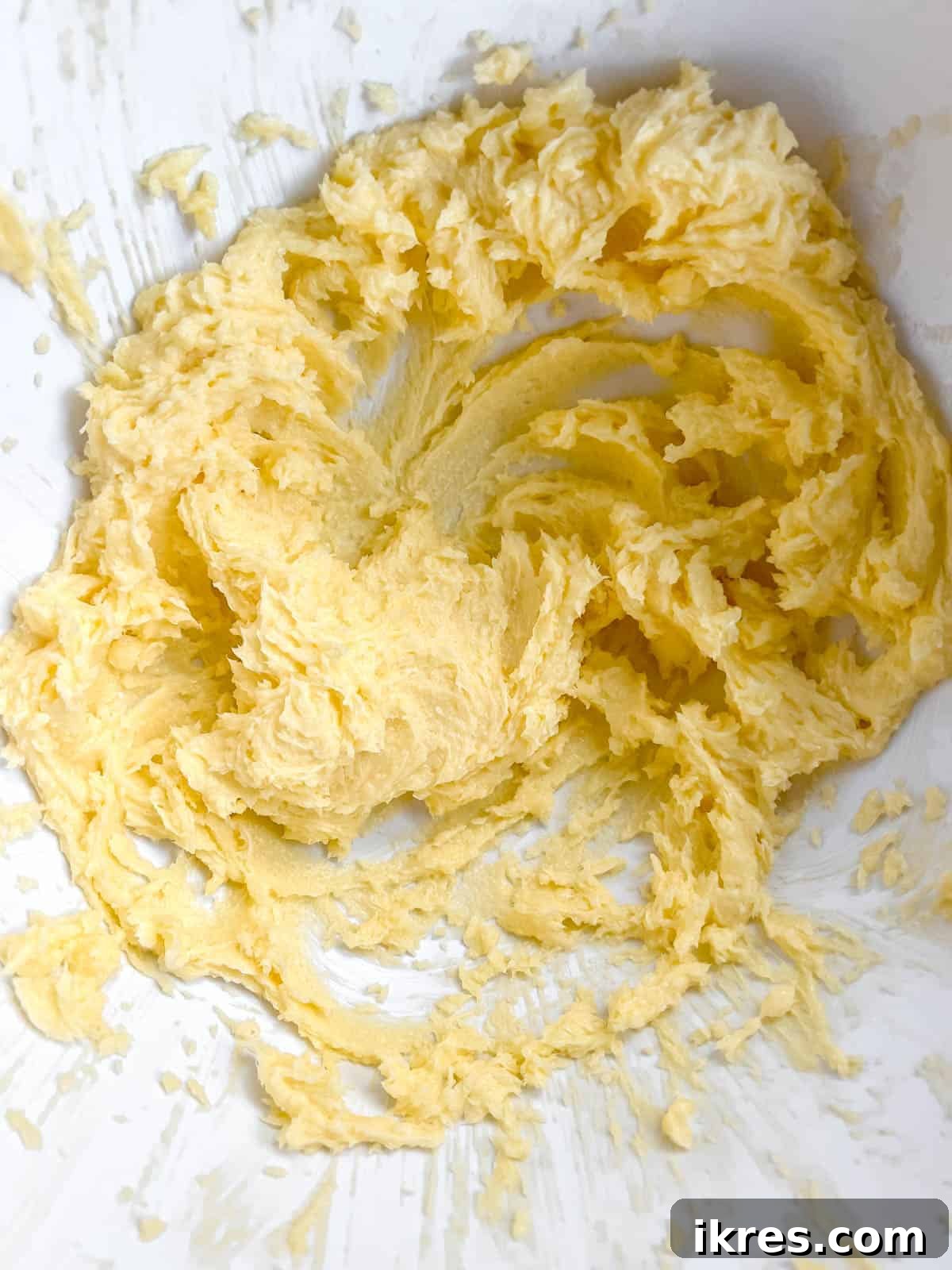 Vanilla extract and a large egg being added to the creamed butter and sugar mixture.