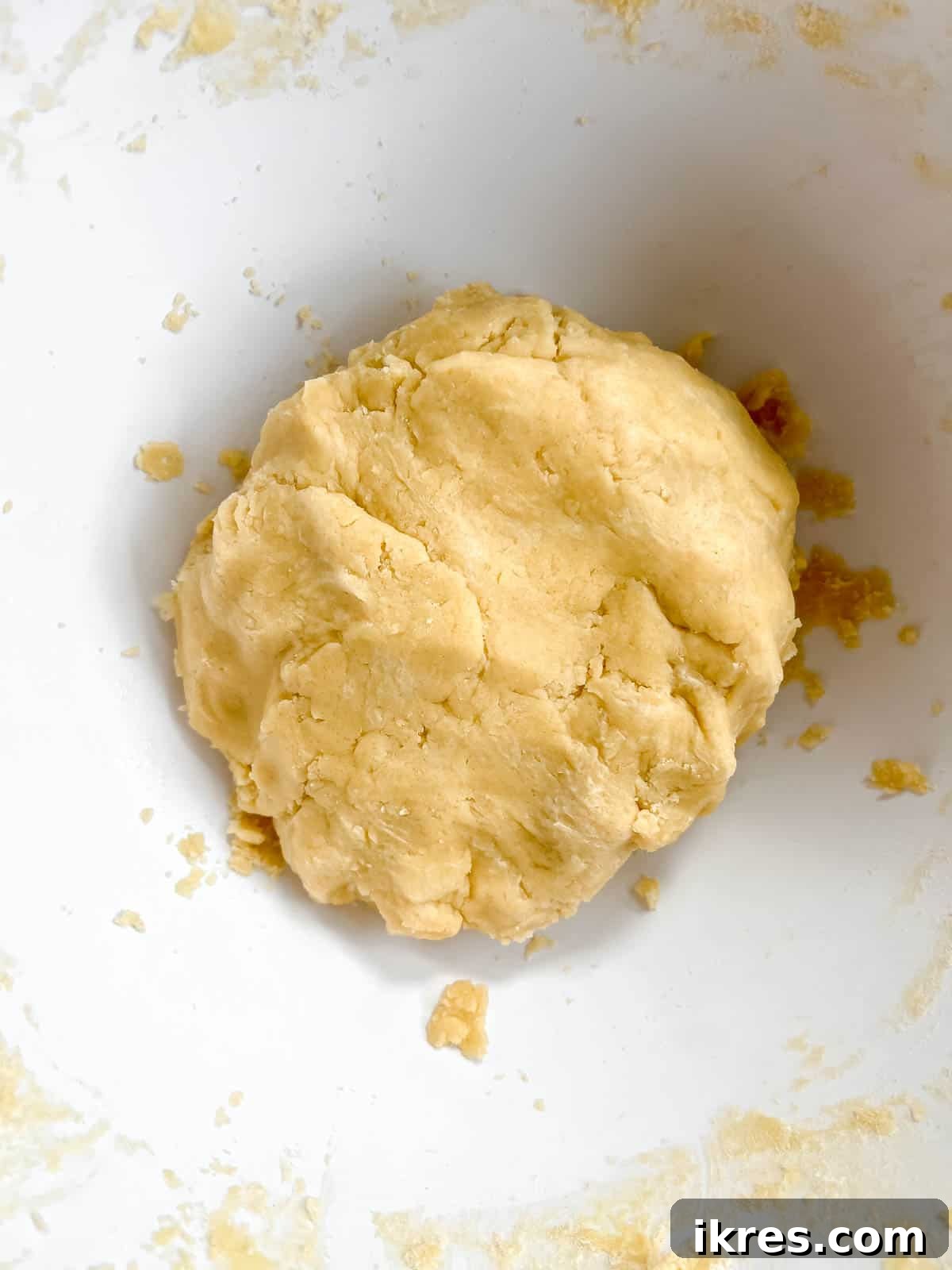 Sable cookie dough being gently mushed by hands to form a cohesive ball after adding water.