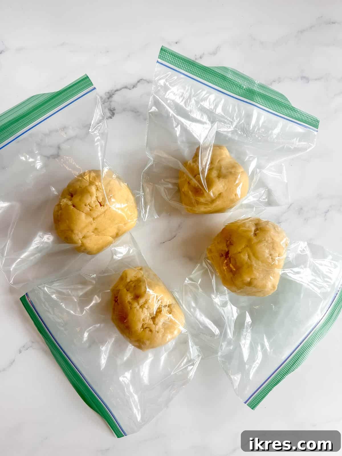 Divided sable cookie dough portions wrapped in plastic, ready for refrigeration.