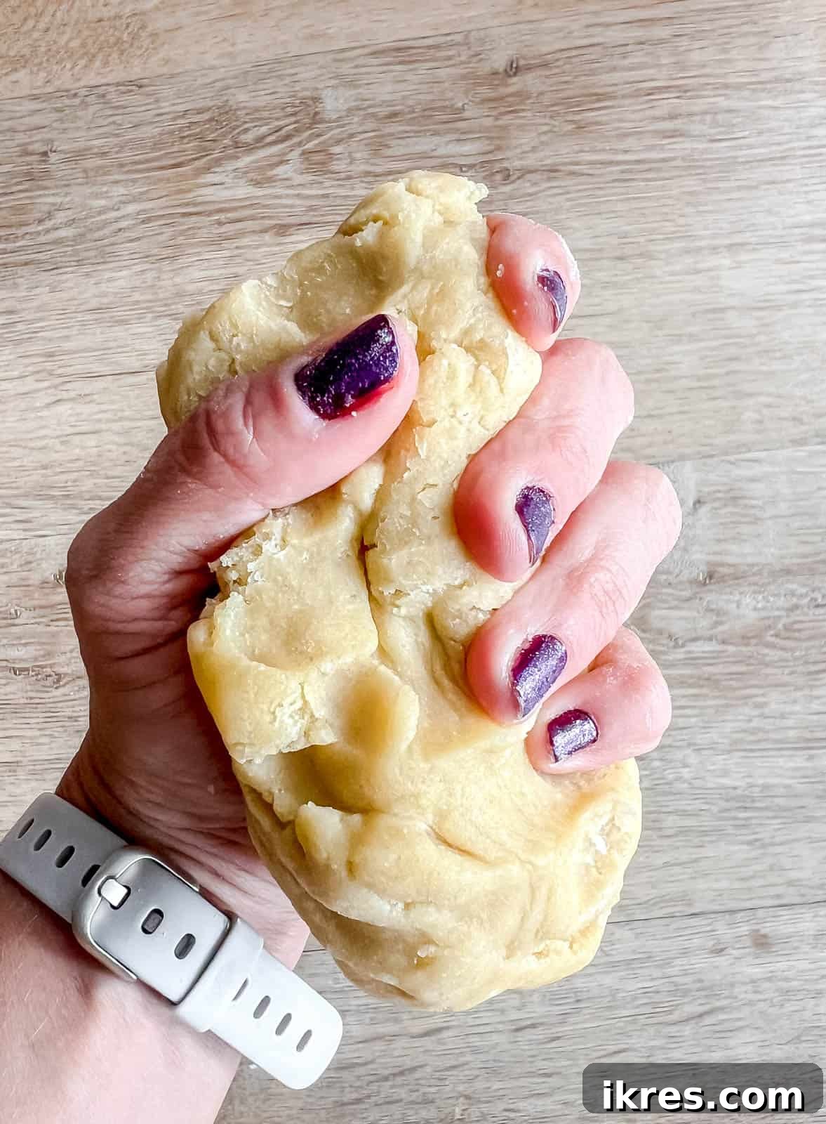 A piece of chilled sable cookie dough being warmed and softened by hand before rolling.
